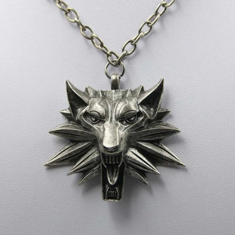 Silver wolf head pendant on a chain against a light gray background