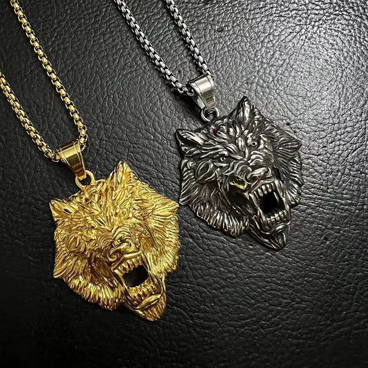 Two wolf head pendants, one gold and one silver, on a black leather background.