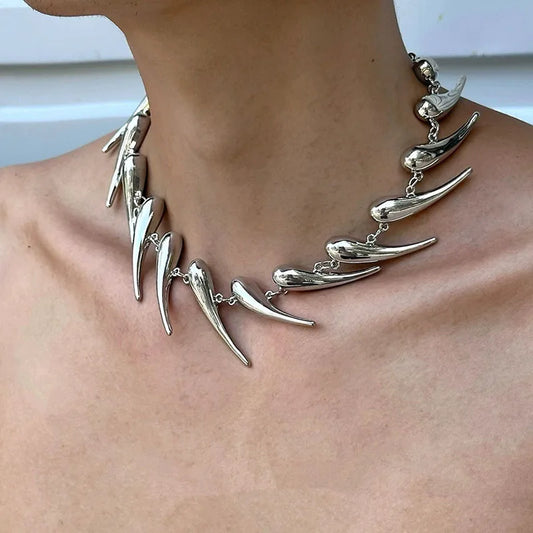 Silver necklace with large, wolf tooth teeth on a person's neck.