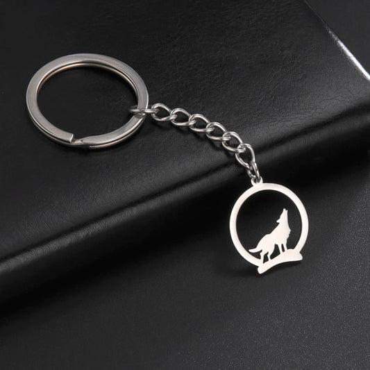 Silver keychain with wolf design on a black surface