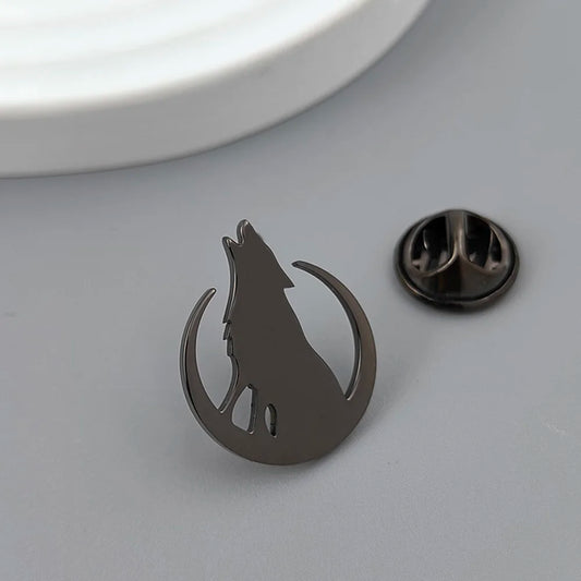 Metallic wolf silhouette lapel pin on a gray surface