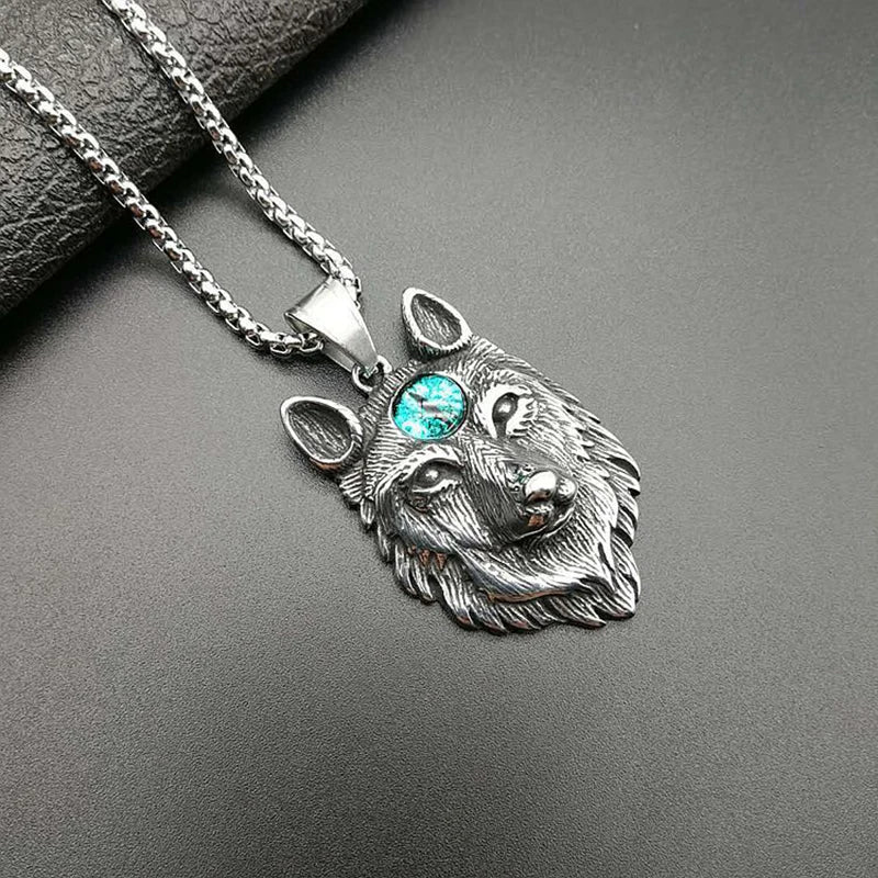 Silver wolf head pendant with a gemstone on a dark surface