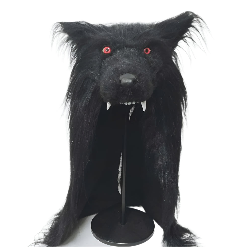 Black furry wolf head with red eyes and white teeth on a stand against a white background