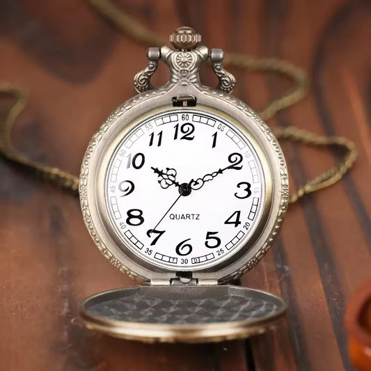 Vintage pocket watch with a white face and gold casing on a wooden surface.