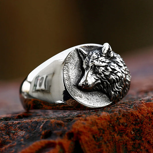 Silver ring with wolf head design on a textured surface