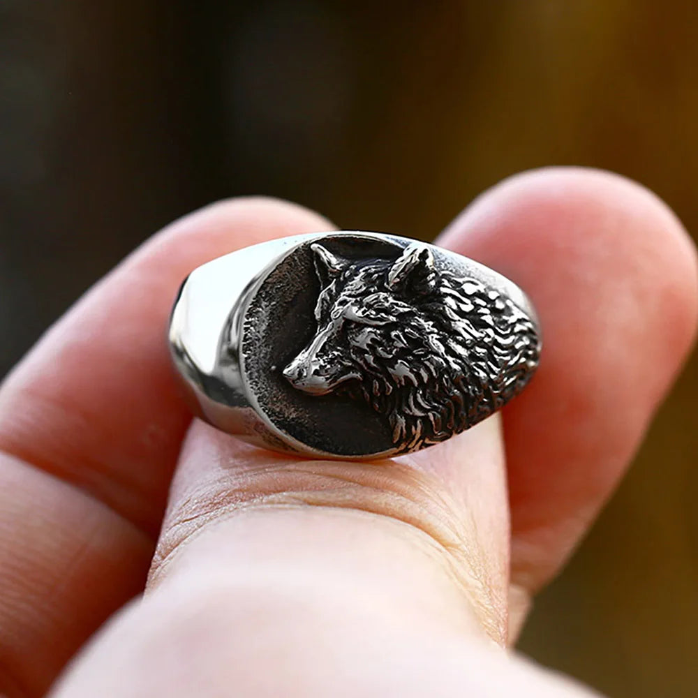 Silver wolf head ring on a finger with a blurred background