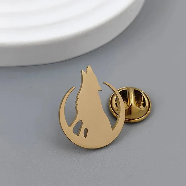 Gold wolf-shaped lapel pin on a gray surface with a white base.