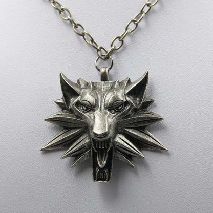 Silver wolf head pendant on a chain against a light gray background