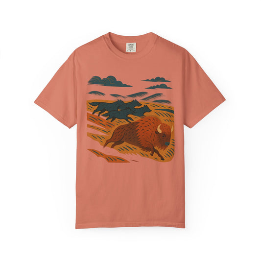 Graphic t-shirt with dynamic wolf pack in motion across grasslands, chasing a bison, printed on soft cotton with relaxed fit and flowing design.