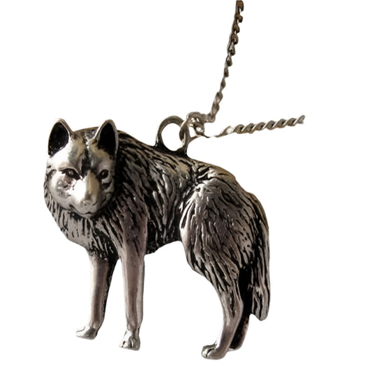 Silver wolf pendant on a chain against a neutral background