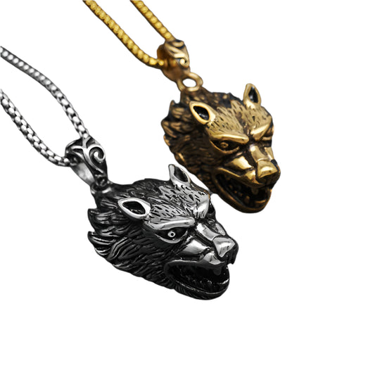 Two wolf head pendants, one gold and one silver, on a white surface.