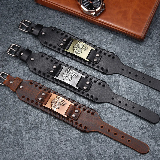 Three leather wristbands with metal bracelets with wolf design on a textured surface.