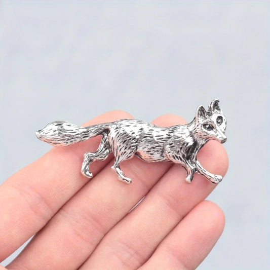 Silver fox figurine held in a hand against a light blue background