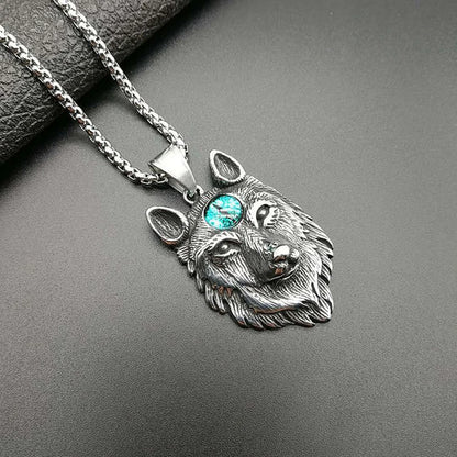 Silver wolf head pendant with a gemstone on a dark surface