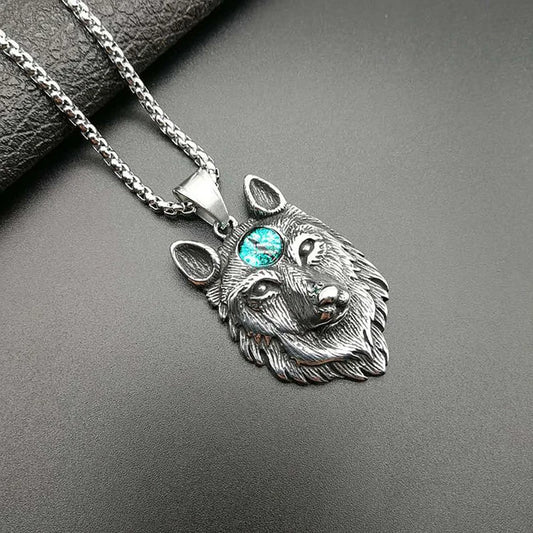 Silver wolf head pendant with a gemstone on a dark surface
