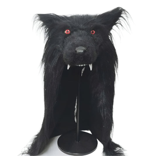 Black furry wolf head with red eyes and white teeth on a stand against a white background