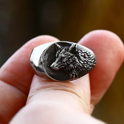 Silver wolf head ring on a finger with a blurred background